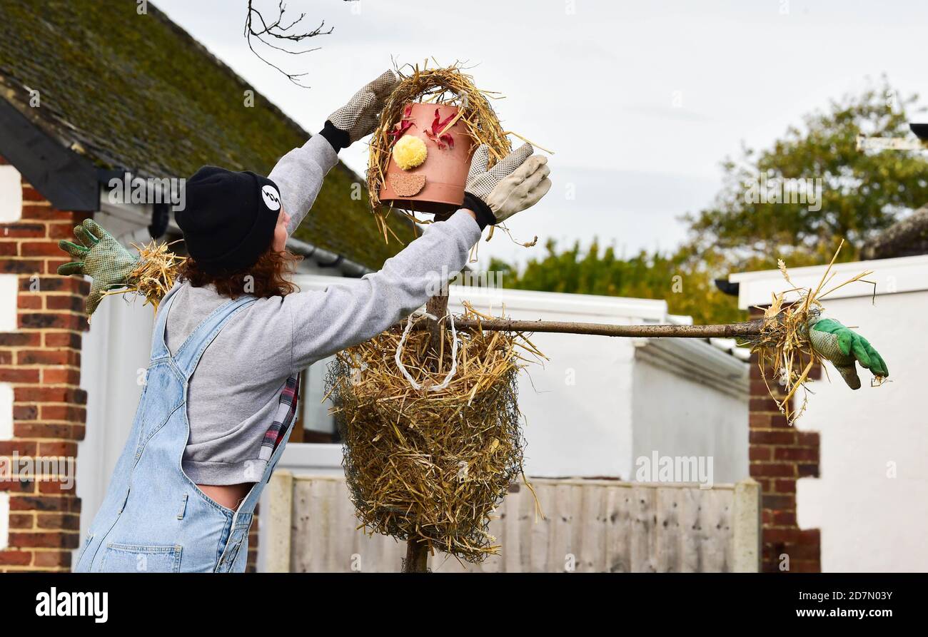 Worthing UK 24th October 2020 - Sophie Worgon puts the final touches one of the scarecrows which have appeared around the village of Ferring near Worthing this weekend as their Scarecrow Festival takes place this week : Credit Simon Dack / Alamy Live News Stock Photo