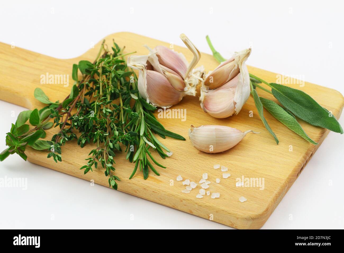 Fresh herbs on wooden board on white background (coriander, thyme, rosemary, sage) and garlic cloves Stock Photo