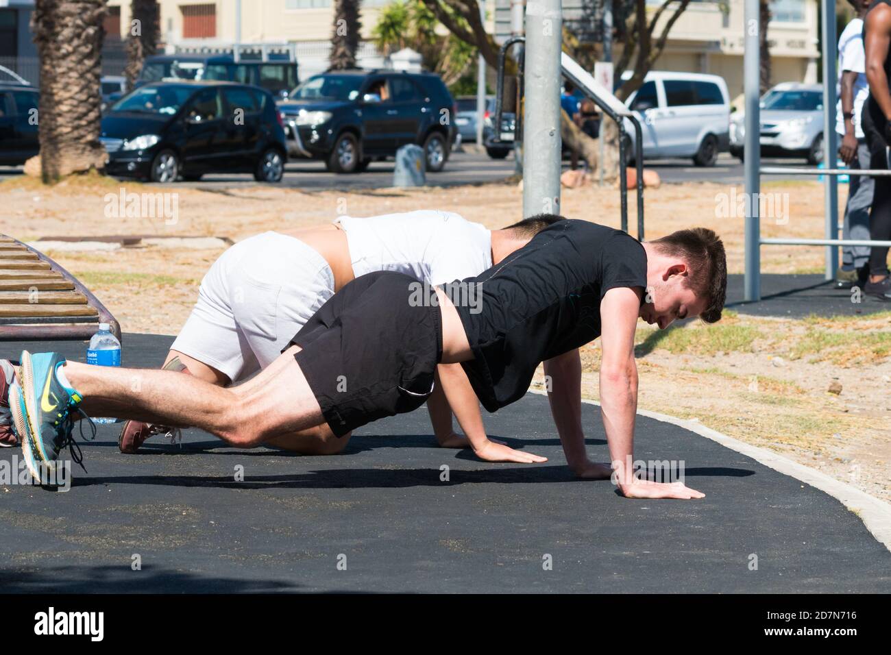two young men doing pushups outdoors during an exercise or gym training session concept health and fitness lifestyle Stock Photo