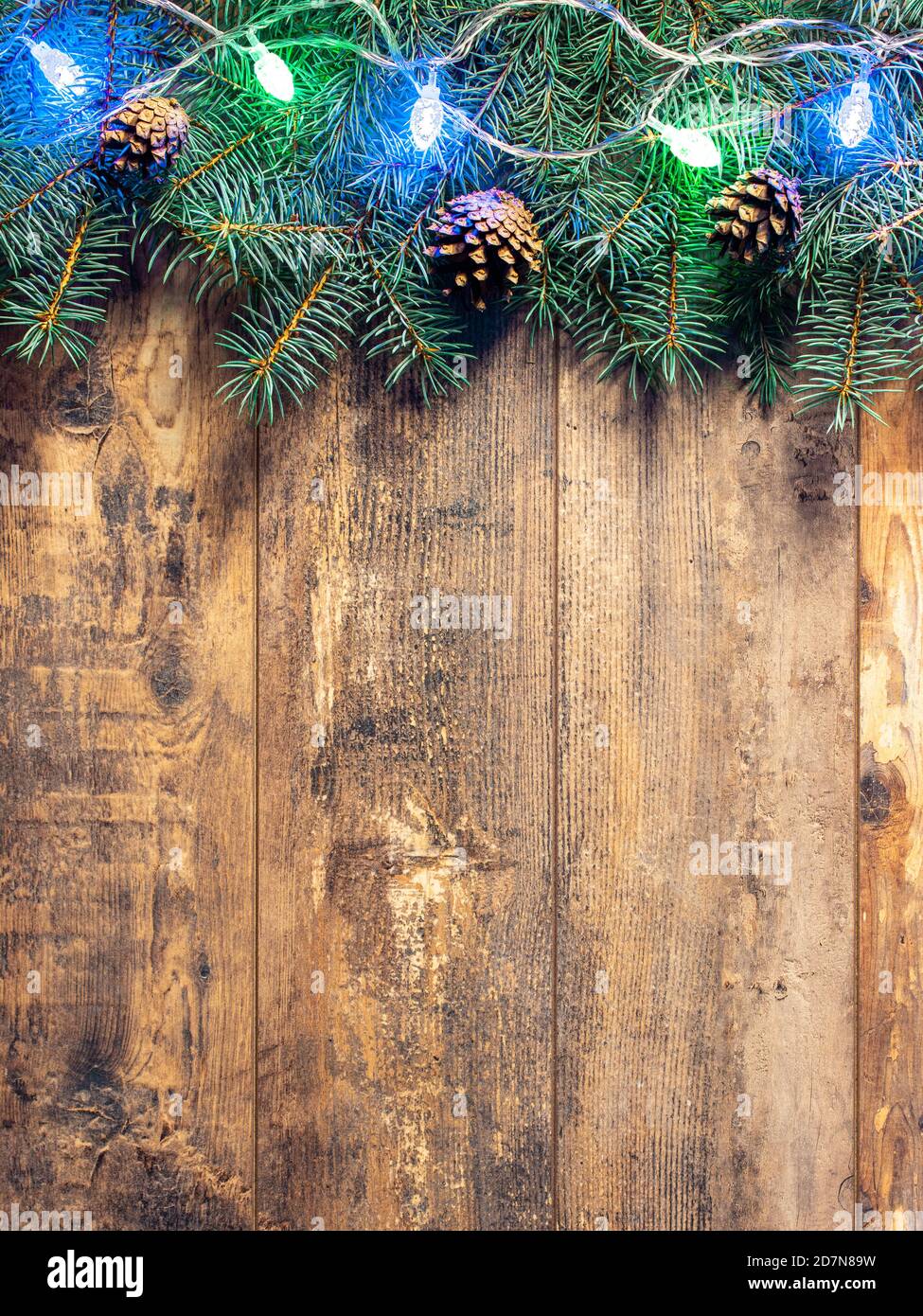 green fir branches and Christmas lights on dark wooden table background ...