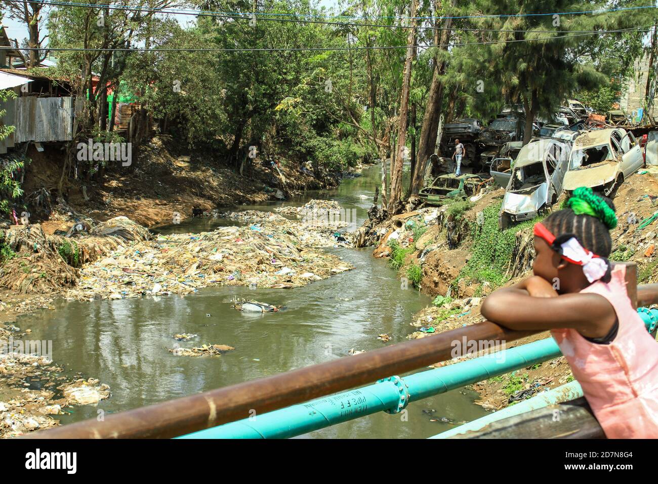 A young girl looks at a section of  the heavily polluted Nairobi River that passes through Dandora dumpsite in the outskirts of Nairobi.Dandora dumpsite which is Nairobi’s biggest dumpsite receives an average of 2,000 metric tonnes of waste daily, most of it being mixed waste composed of largely compostable, metal, electronic, plastic among others. Recently there has been concern from Kenyans after a leaked letter written by the American Petro-Chemical Lobby Group, urging American Trade Negotiators to request Kenyan government to lessen its tough stance on plastic restrictions and to make Keny Stock Photo