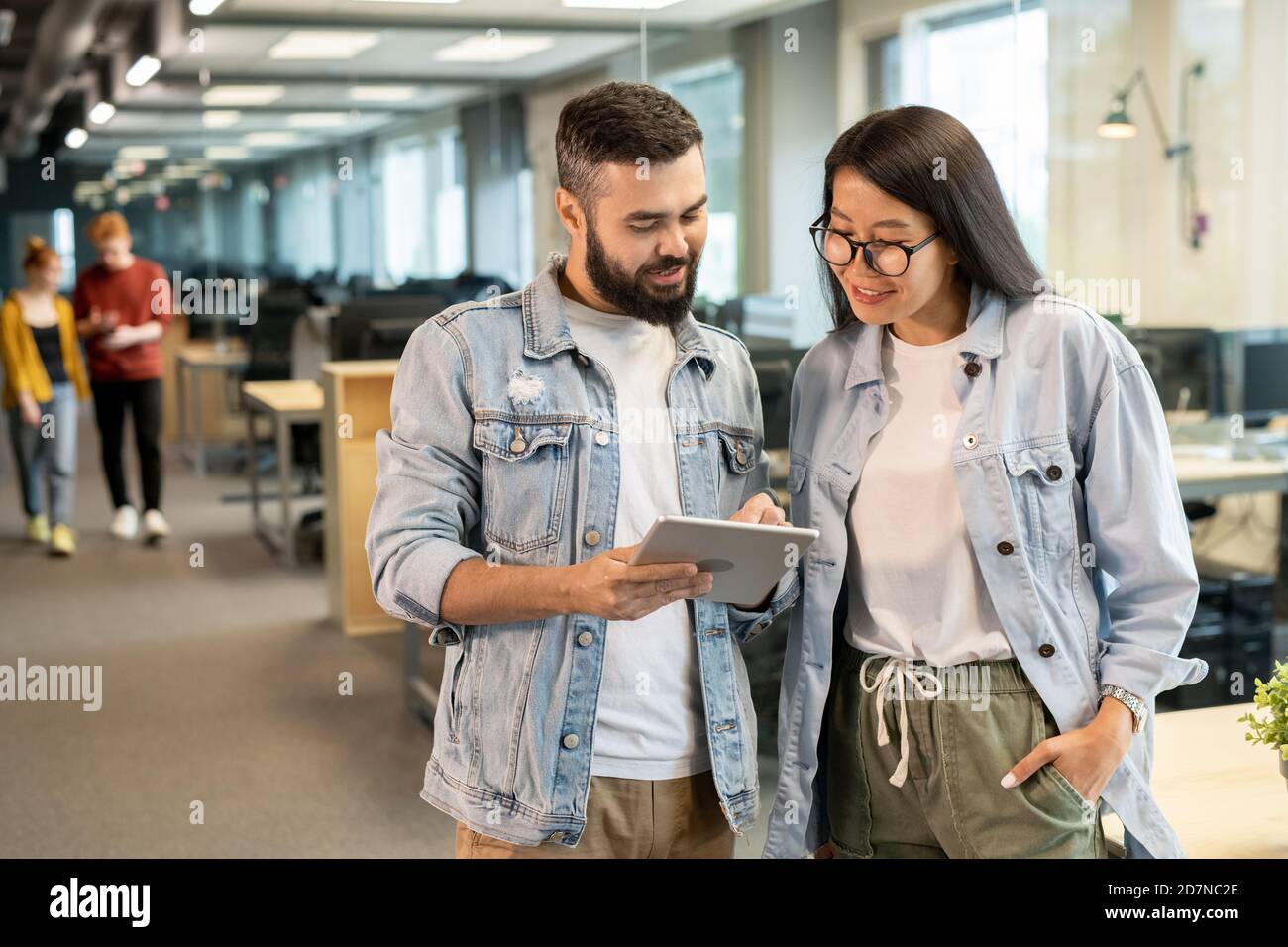 Two happy young intercultural office managers discussing working points or ideas Stock Photo