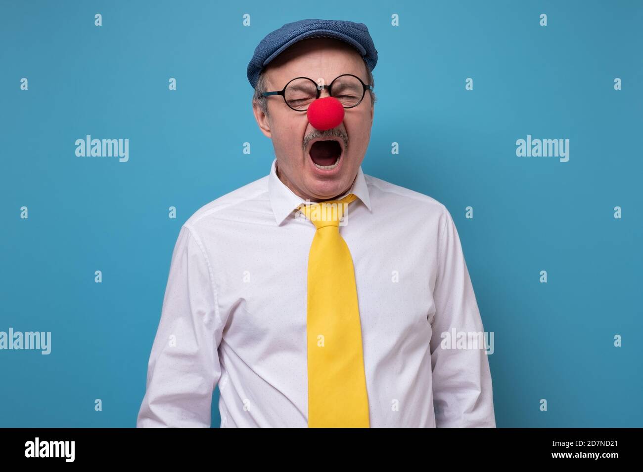 Senior cheerful man with red nose yawning being tired. Stock Photo