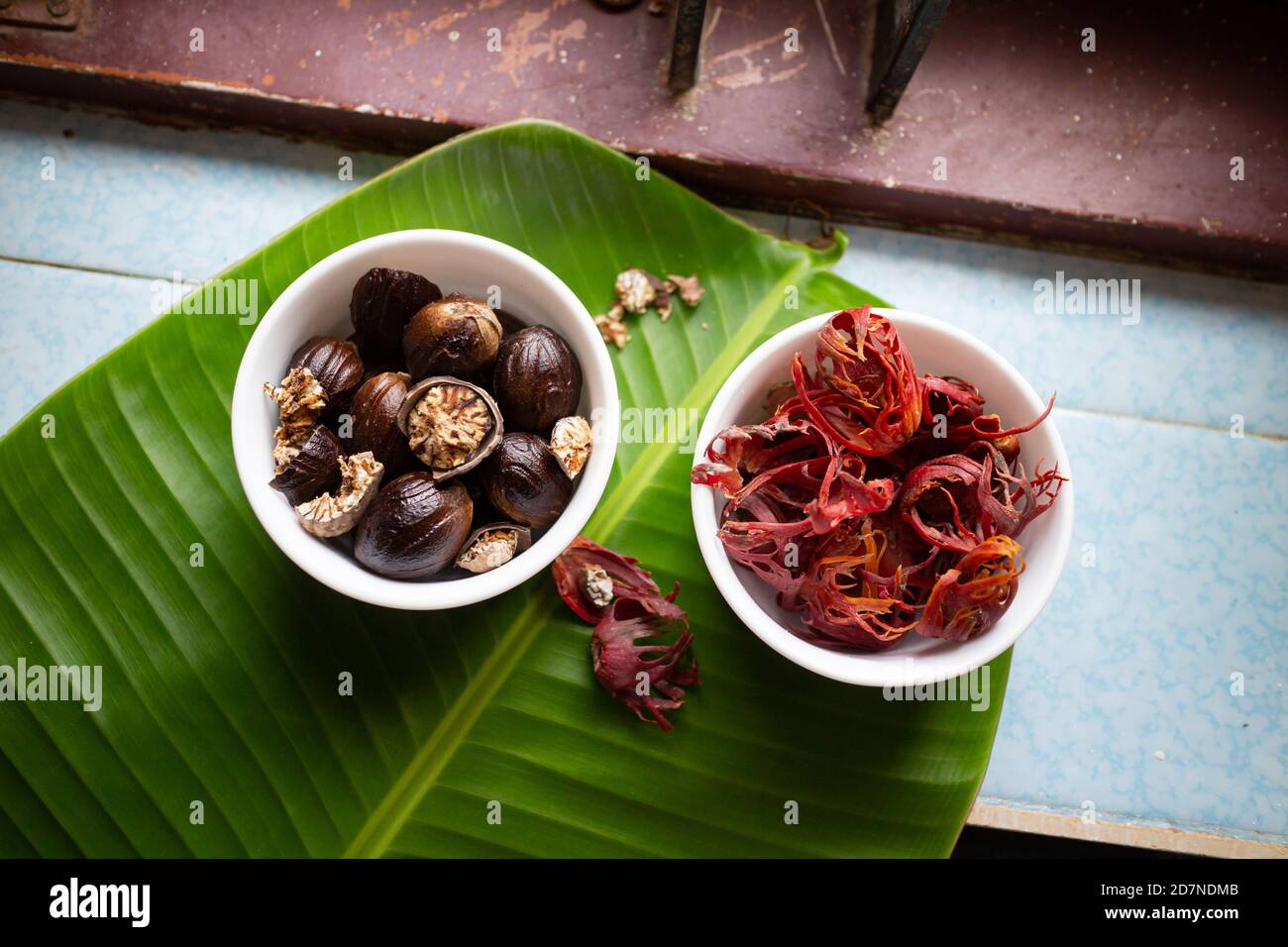 Whole Nutmeg seeds, mace or aril in stone mortar on light blue ...