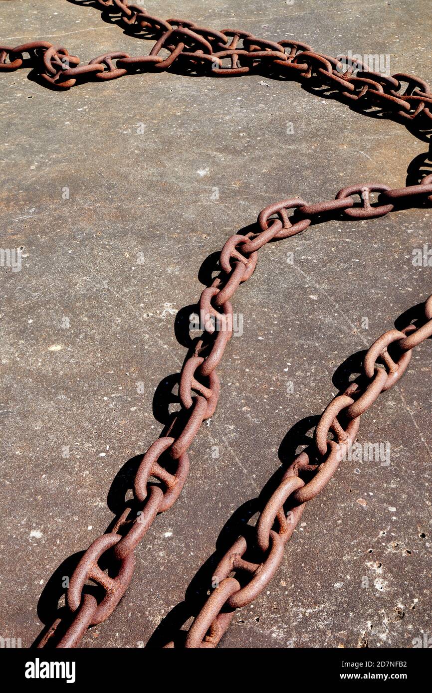 Rusty anchor chain on concrete pier Stock Photo