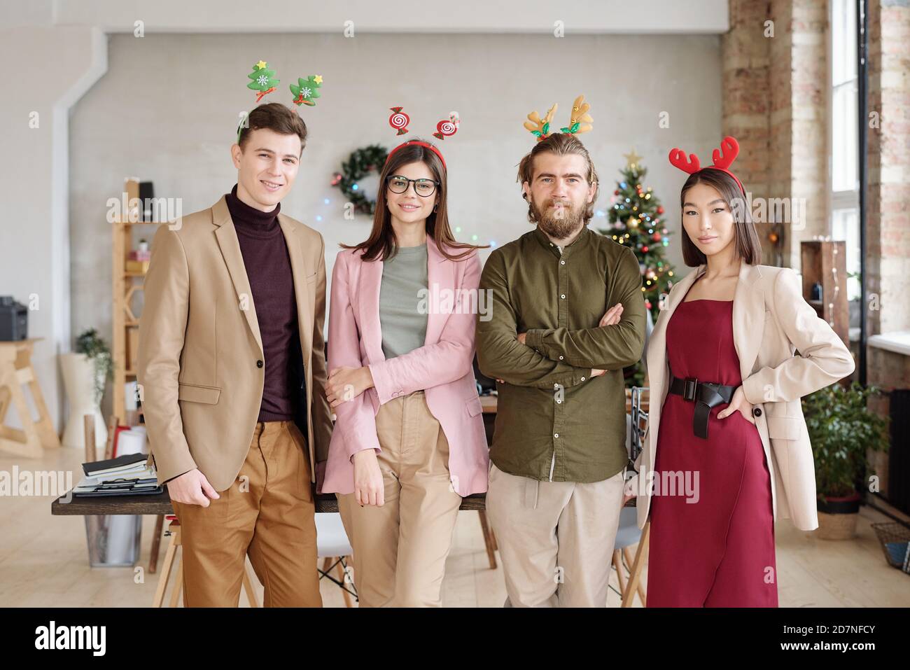 Row of four young white collar workers in smart casualwear and xmas headbands Stock Photo