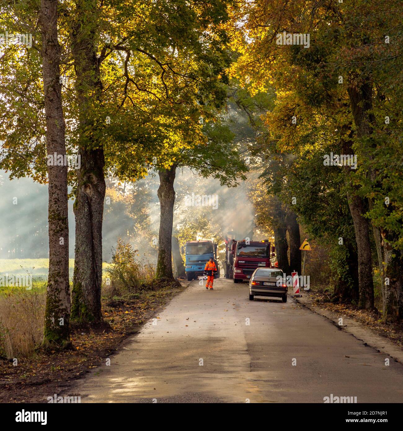 Workers on a small country road in northern Poland in autumn Stock Photo