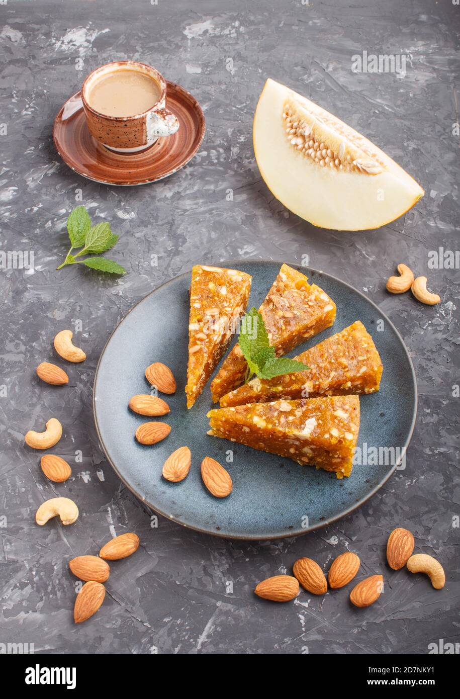 Traditional turkish candy cezerye made from caramelised melon, roasted walnuts, hazelnuts, cashew, pistachios in blue ceramic plate and a cup of coffe Stock Photo