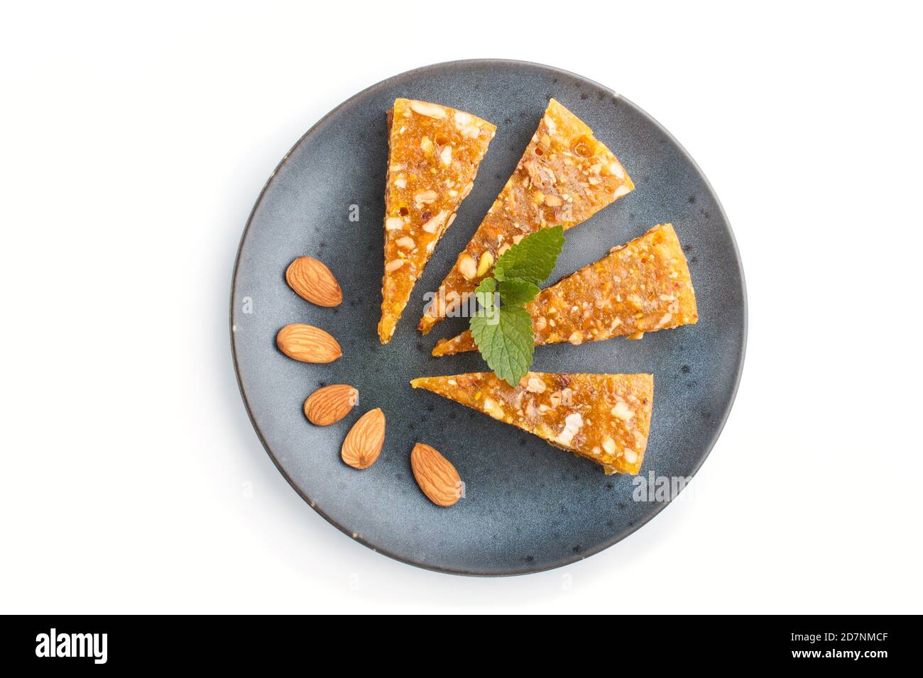 Traditional turkish candy cezerye made from caramelised melon, roasted walnuts, hazelnuts, pistachios in blue ceramic plate isolated on white backgrou Stock Photo