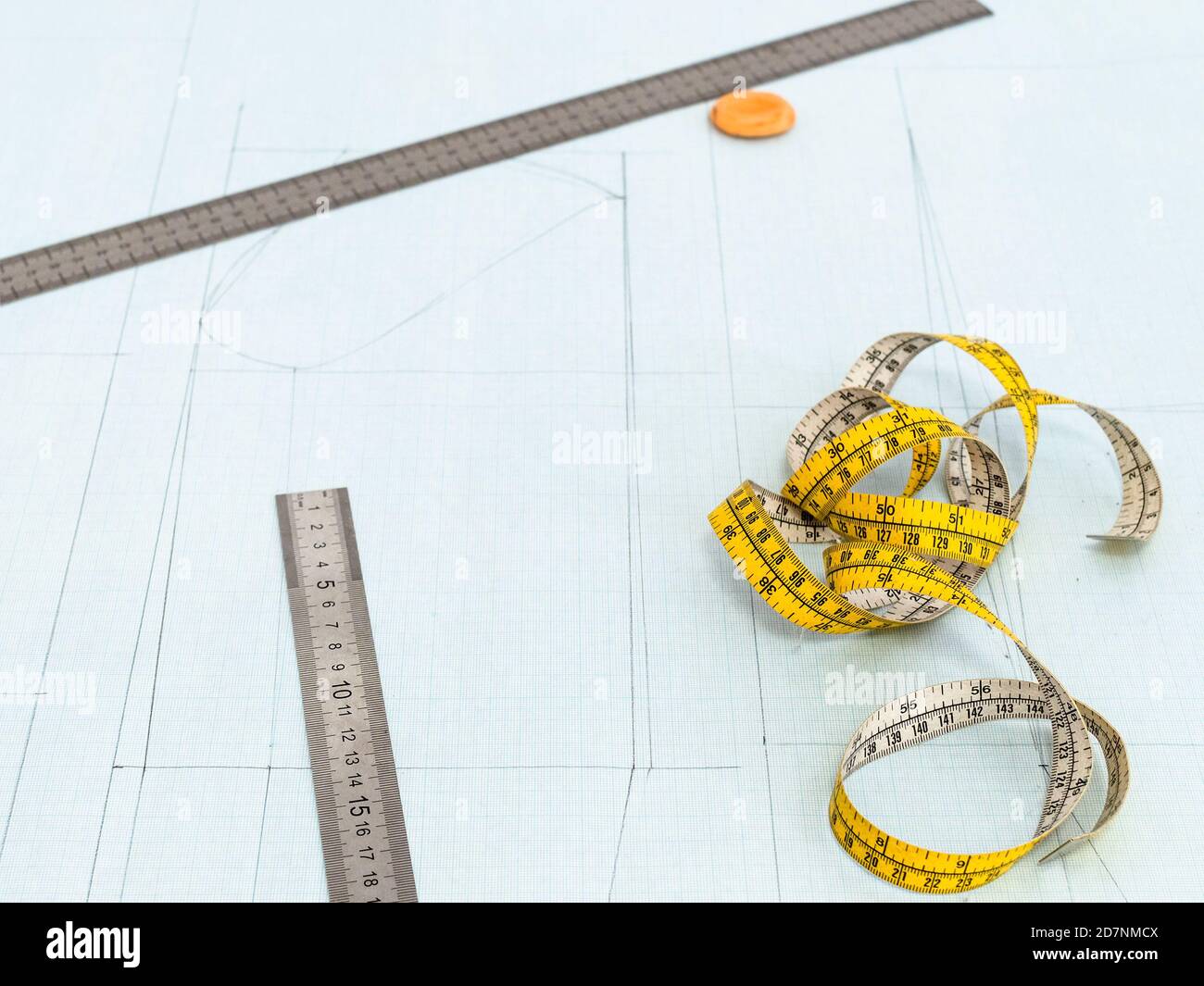 tailor's measure tape, rulers and eraser on pattern layout of dress