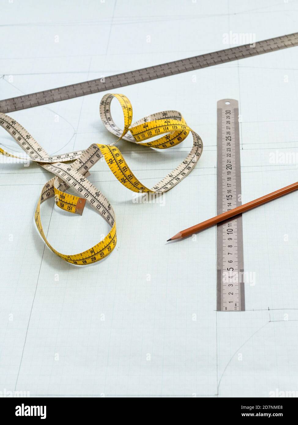 measuring tape, rulers and pencil on pattern layout of dress drawn on