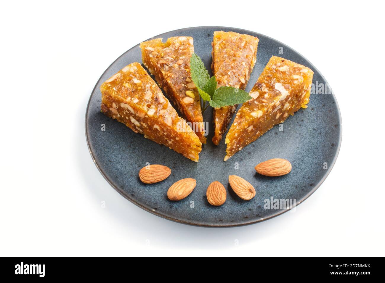 Traditional turkish candy cezerye made from caramelised melon, roasted walnuts, hazelnuts, pistachios in blue ceramic plate isolated on white backgrou Stock Photo