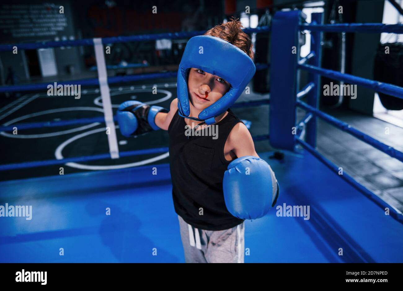 Little boy in protective wear and with nose bleed training in the boxing ring Stock Photo