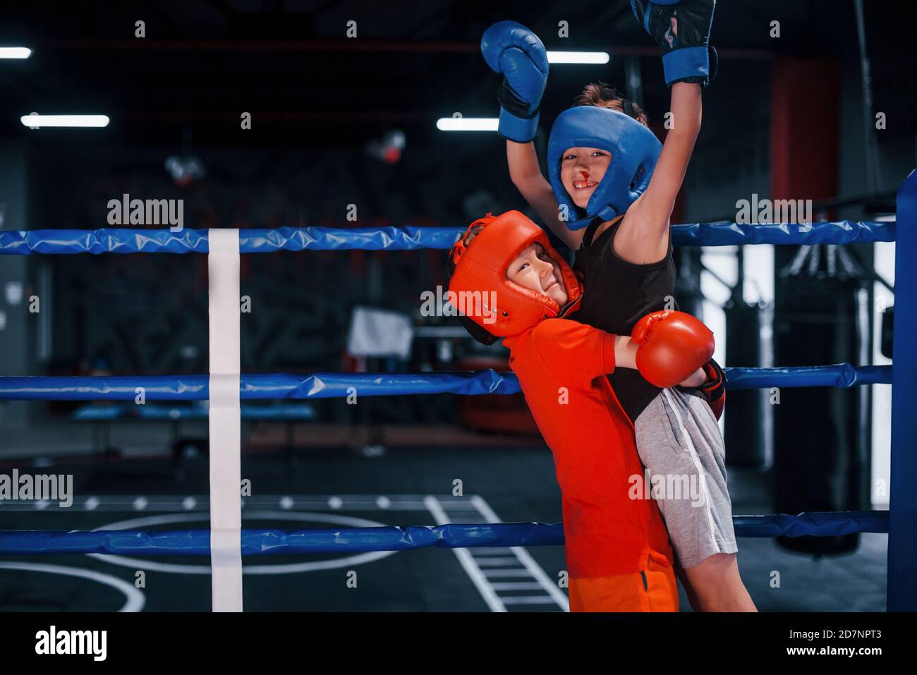 Portrait of two young boys in protective gloves celebrating victory on boxing ring Stock Photo