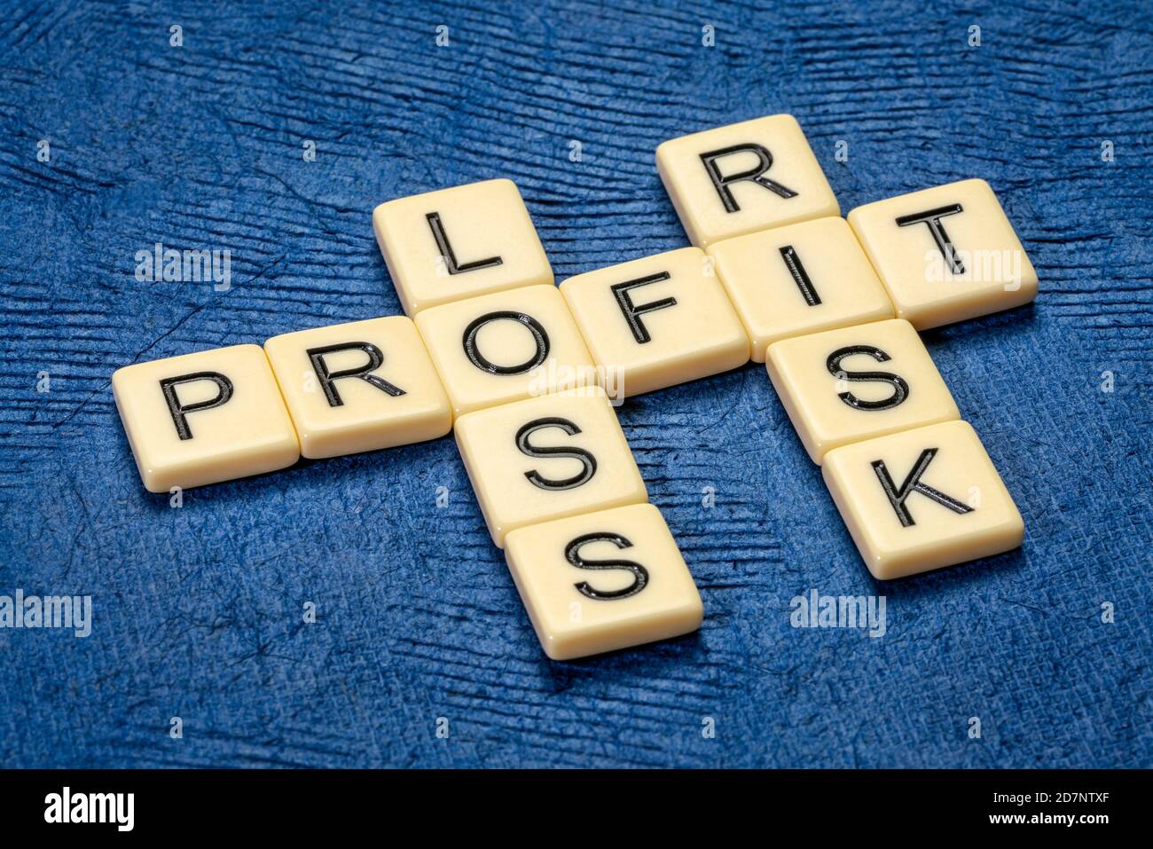 profit, loss and risk crossword in ivory letters against textured handmade bark paper, business, finance and investing concept Stock Photo