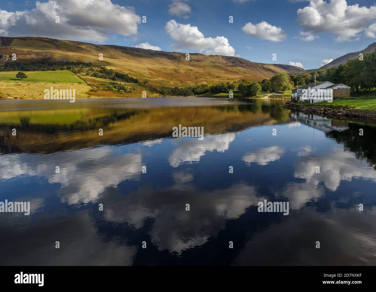 Dovestone reservoir, Greenfield Saddleworth on a clear sunny day with hillls, beautiful reflections and cloud patterns on the hillside. Dark peak. Stock Photo