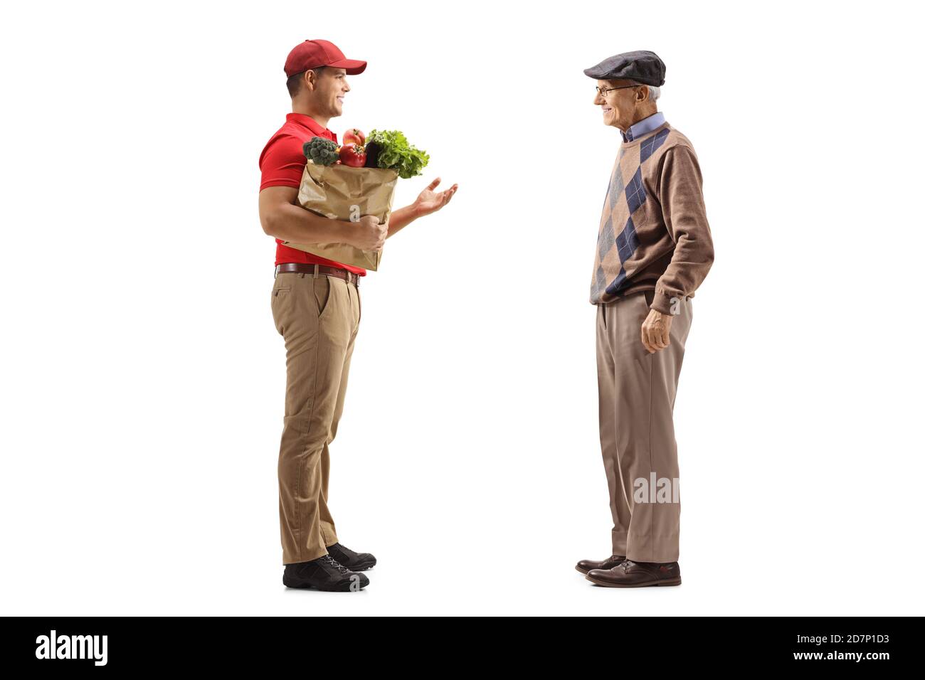 Full length profile shot of a delivery guy with a grocery bag talking to an elderly male customer isolated on white background Stock Photo