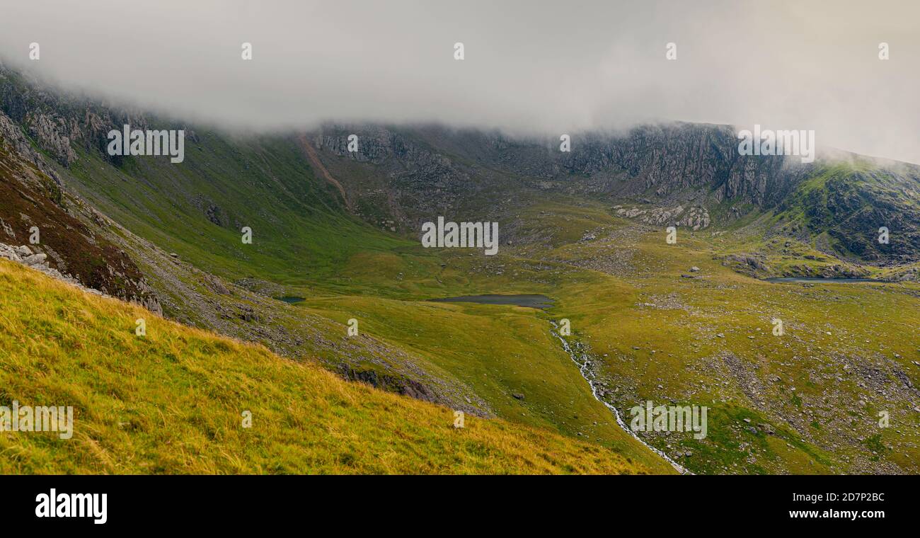Panoramic view at Yr Wyddfa - Snowdon on cloudy day from Ranger Path. Highest mountain range in Wales covered in clouds. Snowdonia National Park. UK. Stock Photo