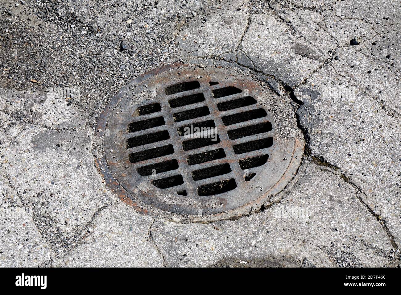 Rusty drainage grate in cracked aspahlt Stock Photo