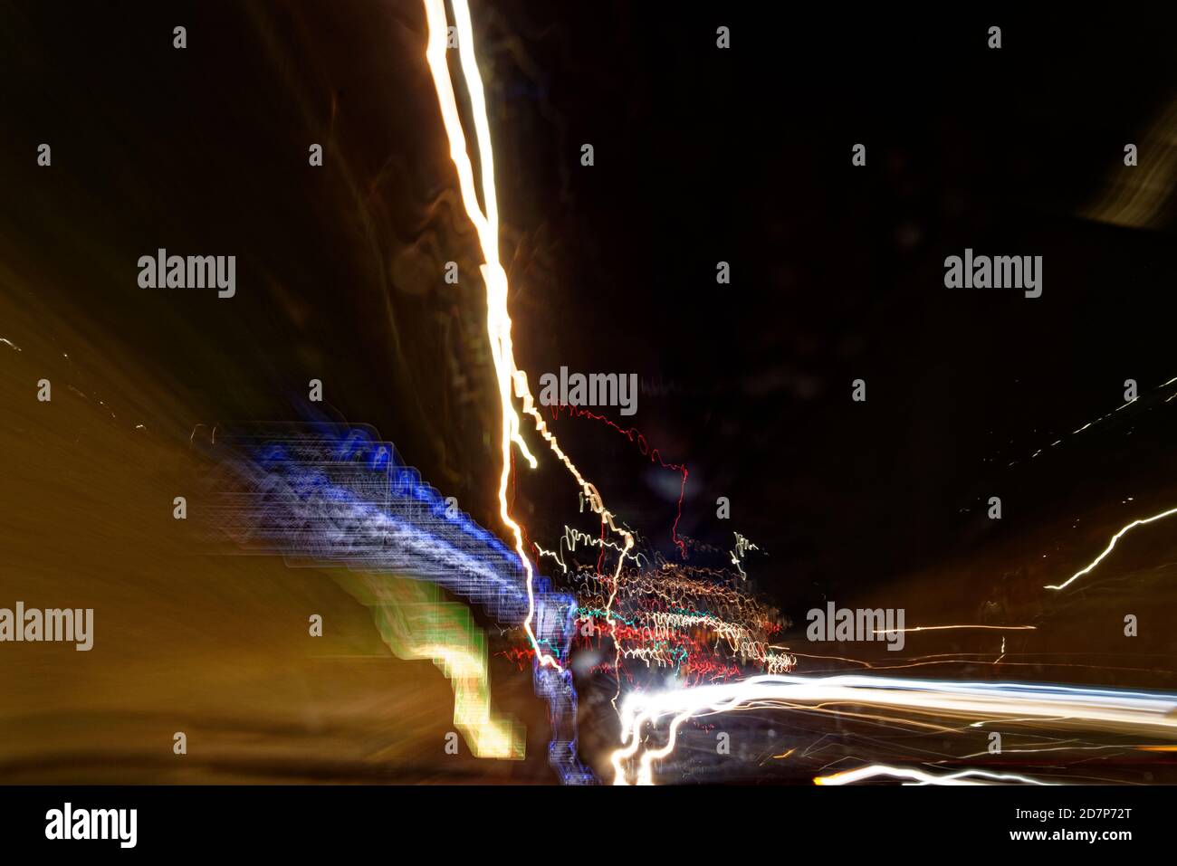 Long exposure light trails as abstract urban background. Different light trails of multicolored street lanterns and passing cars scattering in the dar Stock Photo