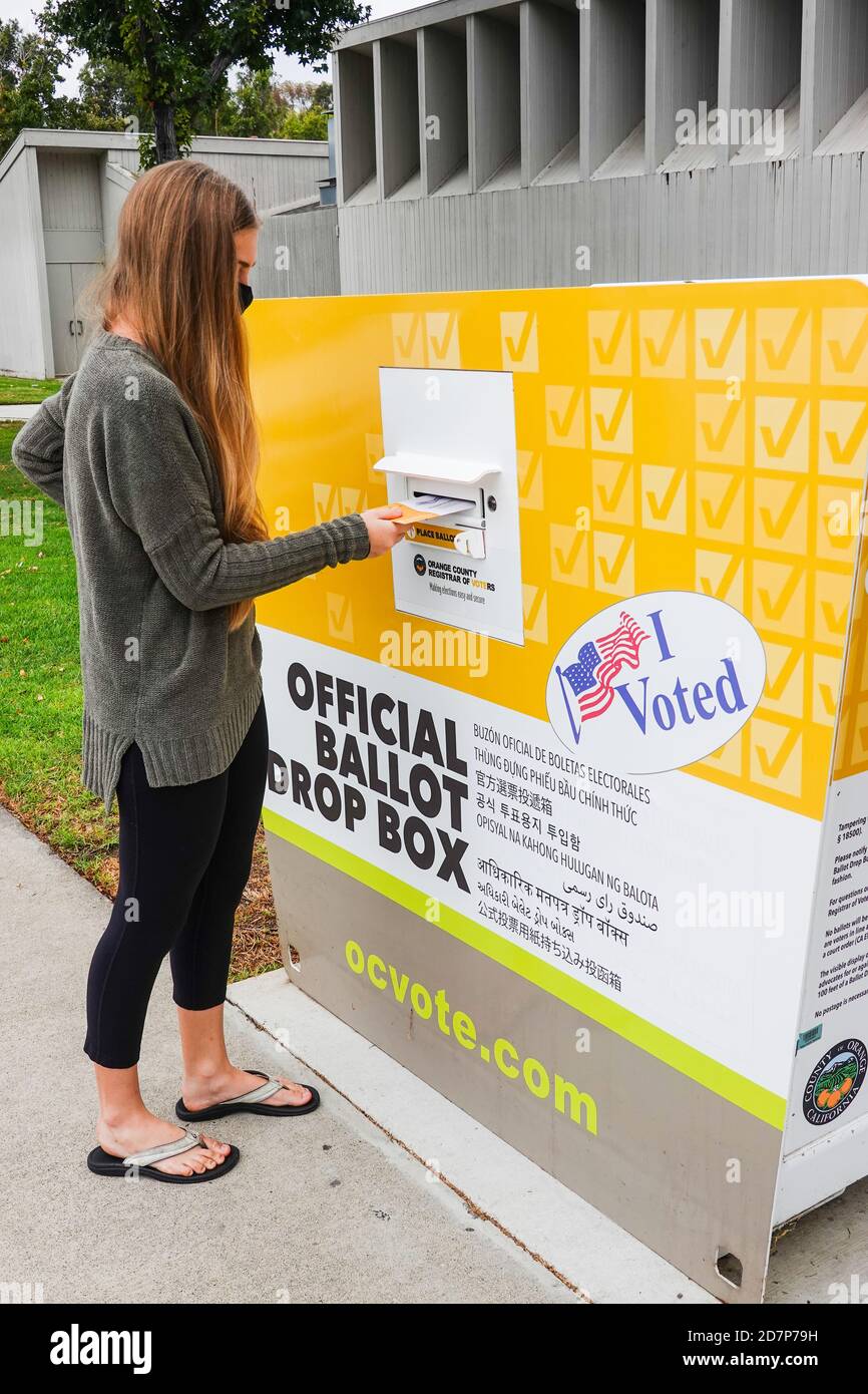 Young American woman voting wearing  a mask and casting early vote at ballot drop box for 2020 US Election in Irvine California. Stock Photo