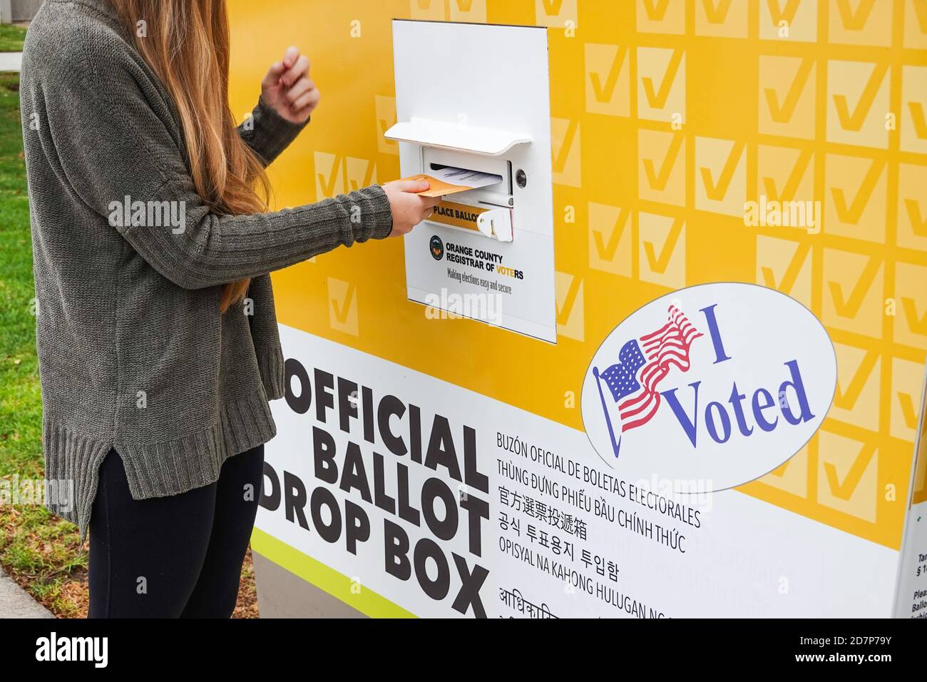 Young American female voter wearing  a mask and casting early vote at ballot drop box for 2020 US Election in Irvine California. Stock Photo