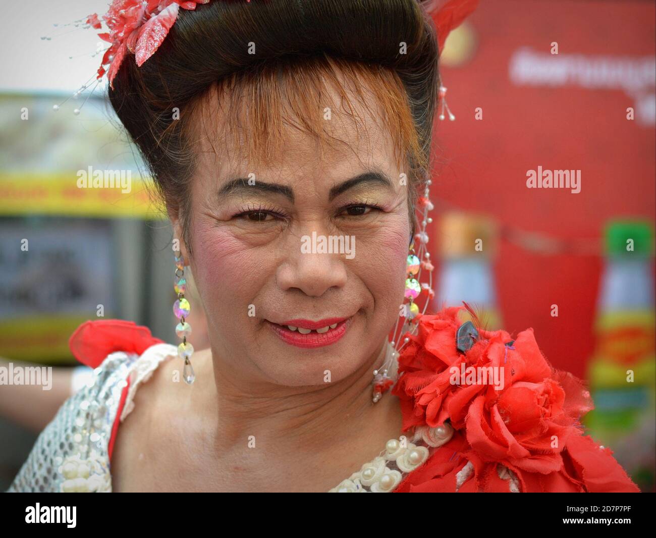 Middle aged dressed up Thai cross-dressing gender queer (kathoey) smiles for the camera in Chinatown during Chinese New Year. Stock Photo