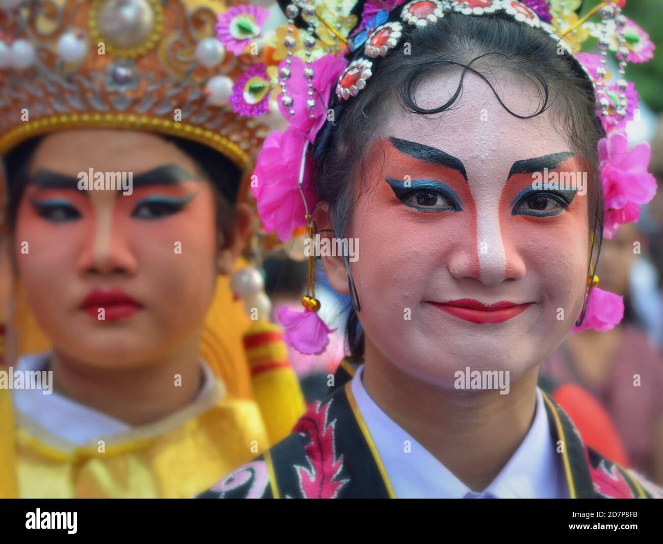 Costumed Thai Chinese female performers with painted traditional Peking opera masks pose for the camera at colorful Chinese New Year street parade. Stock Photo