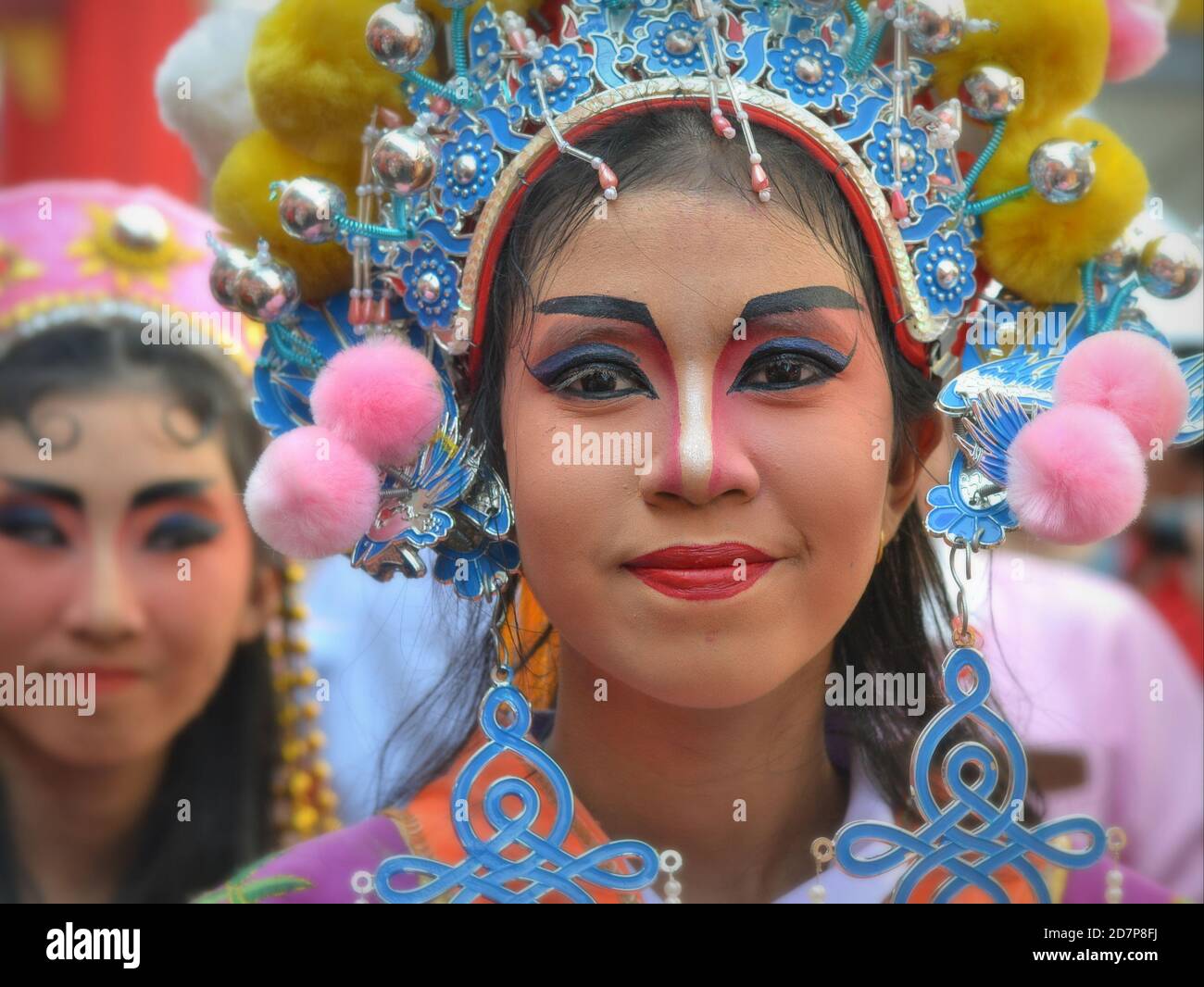 Costumed female Thai Chinese performers with painted traditional Peking opera masks pose for the camera at colorful Chinese New Year street parade. Stock Photo