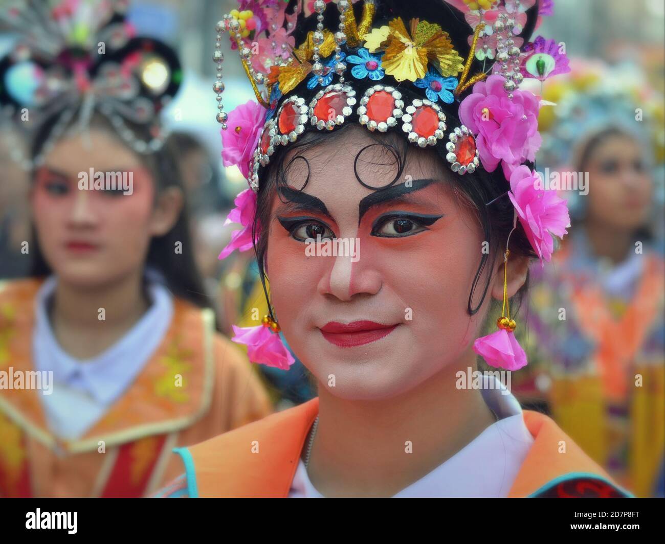 Costumed Thai Chinese female performer with painted traditional Peking opera mask poses for the camera at colorful Chinese New Year street parade. Stock Photo