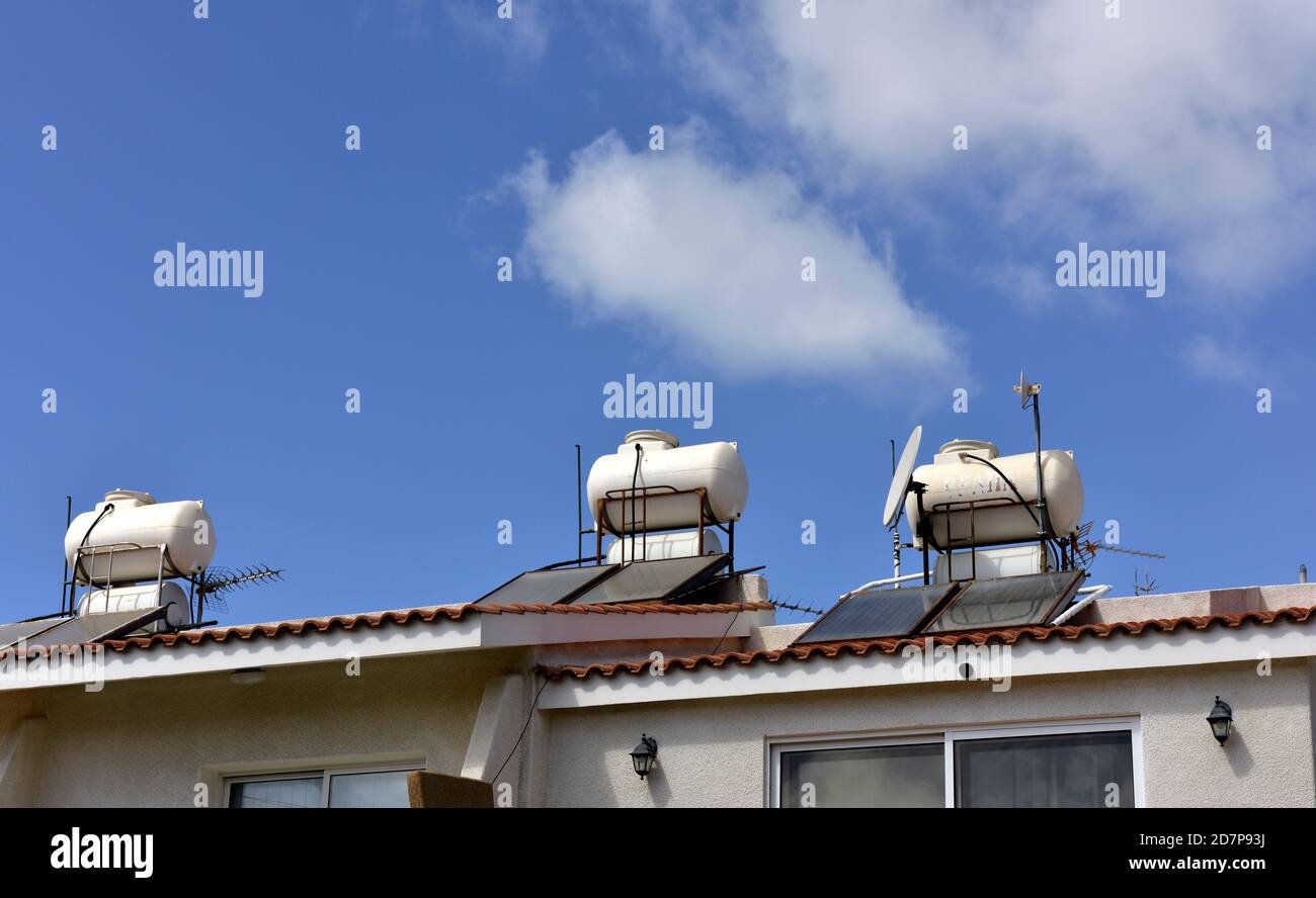 Houses with solar thermal heating hot water storage on the roof along with satellite dish and TV aerial, Cyprus Stock Photo