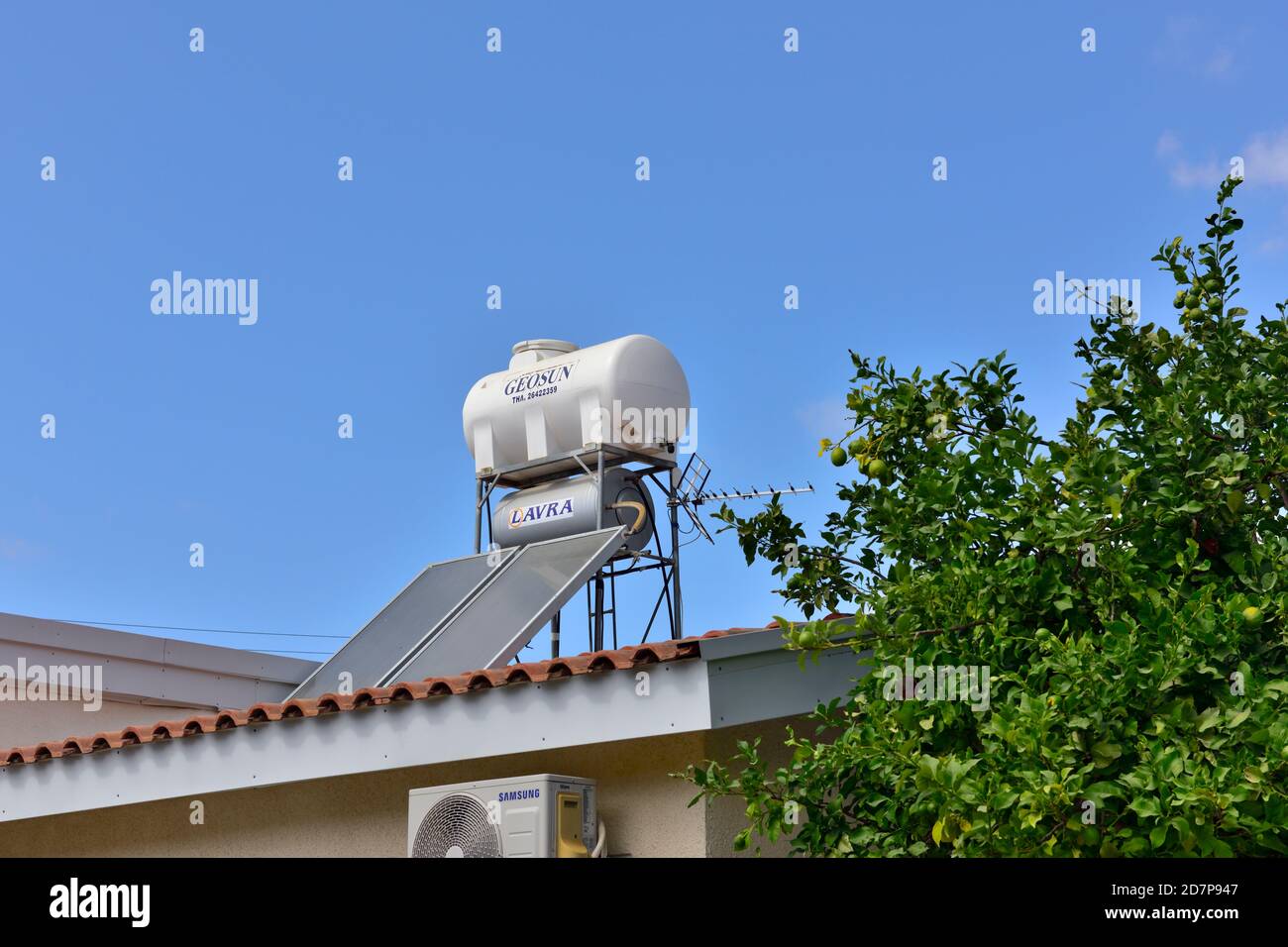 House with solar thermal heating hot water storage on the roof along with TV aerial, next to lemon tree, Cyprus Stock Photo