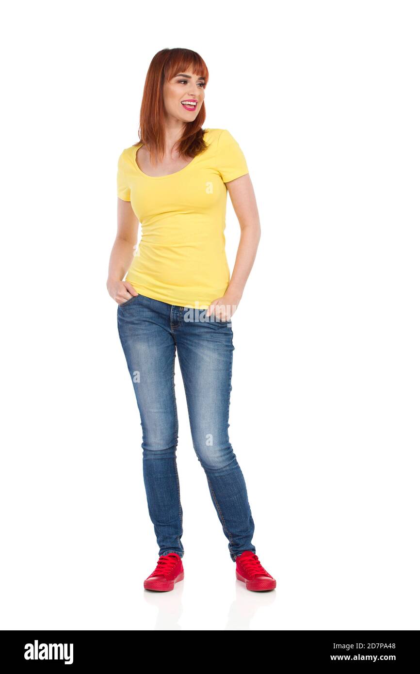 Happy casual young woman in yellow shirt, jeans and red sneakers