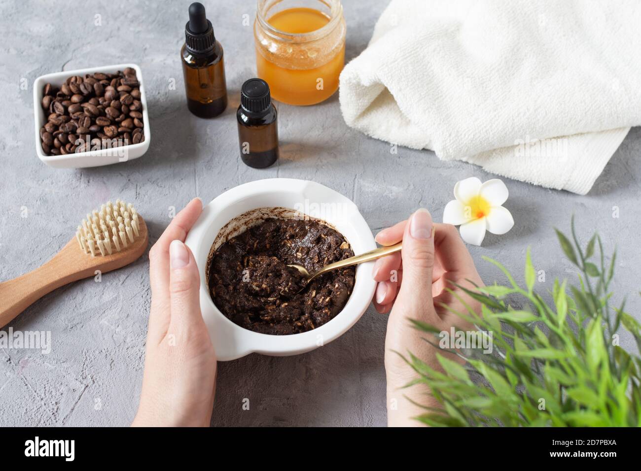 Homemade body scrub made with ground coffee, honey and oatmeal in a jar on gray concrete table. Self-care at home, eco homemade cosmetic for spa and s Stock Photo