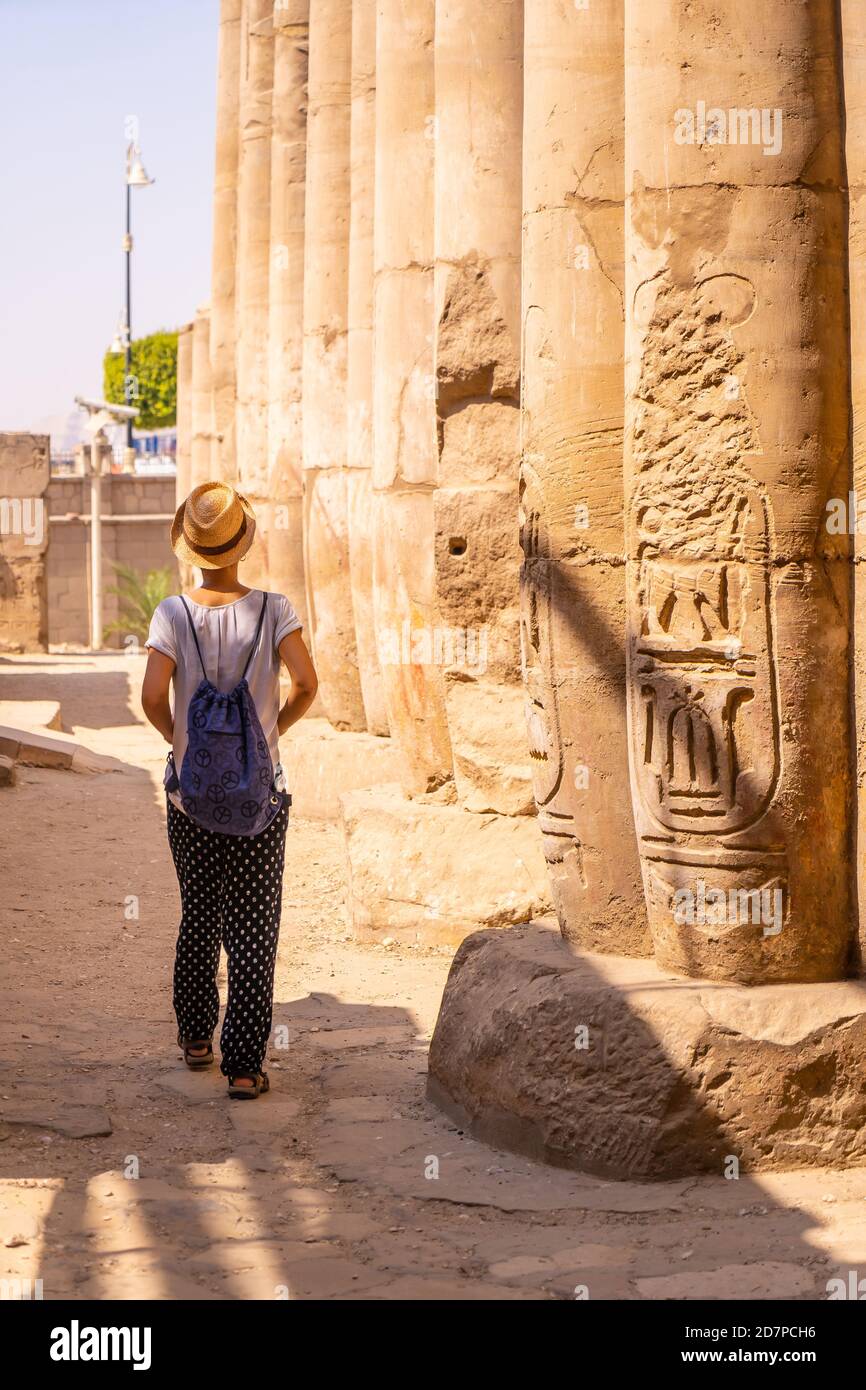 Young female with a backpack and a panama hat walking around the Luxor Temple in Egypt Stock Photo