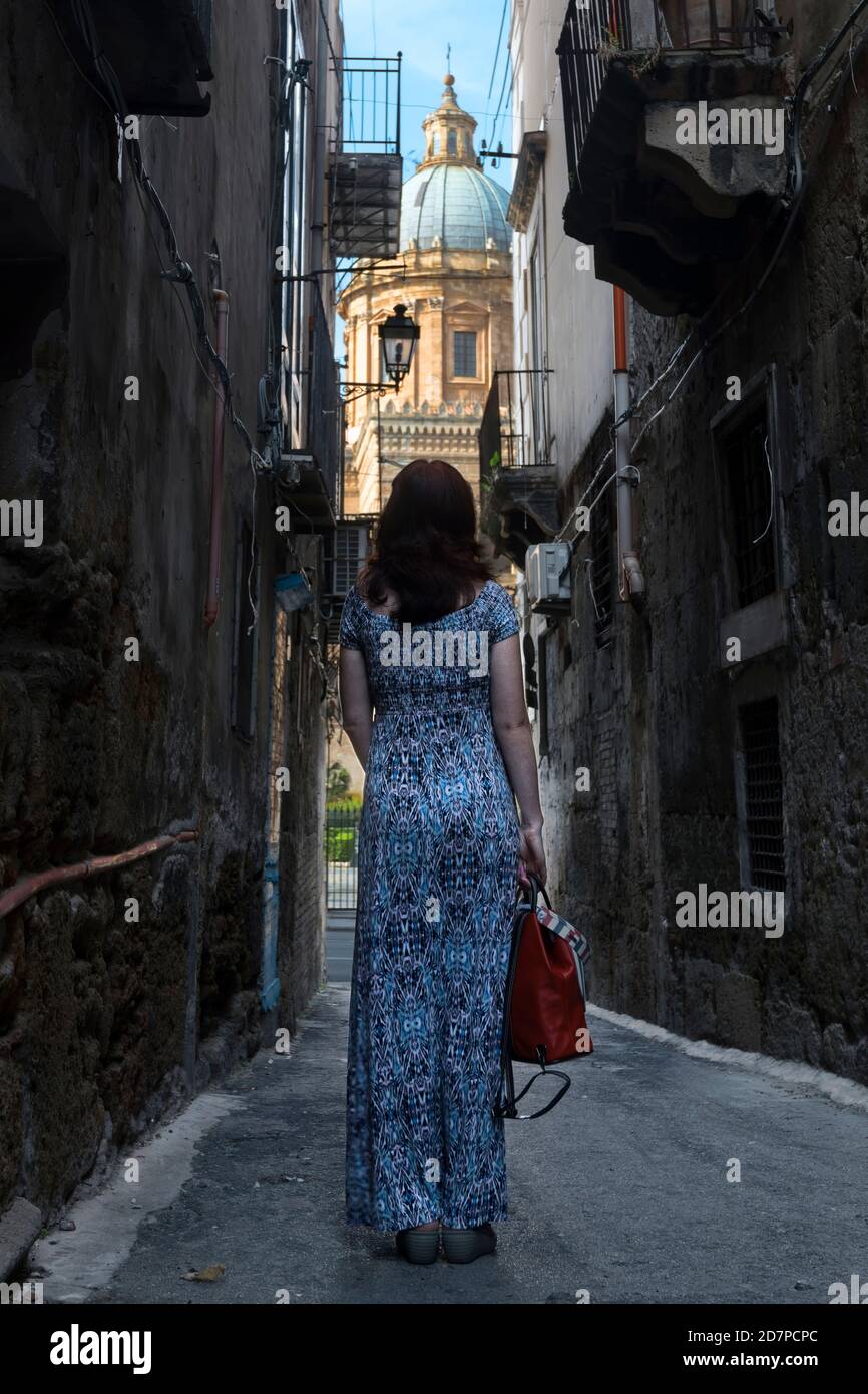 A woman looking at Palermo Cathedral from an old narrow street in Palermo, Sicily, Italy. Stock Photo