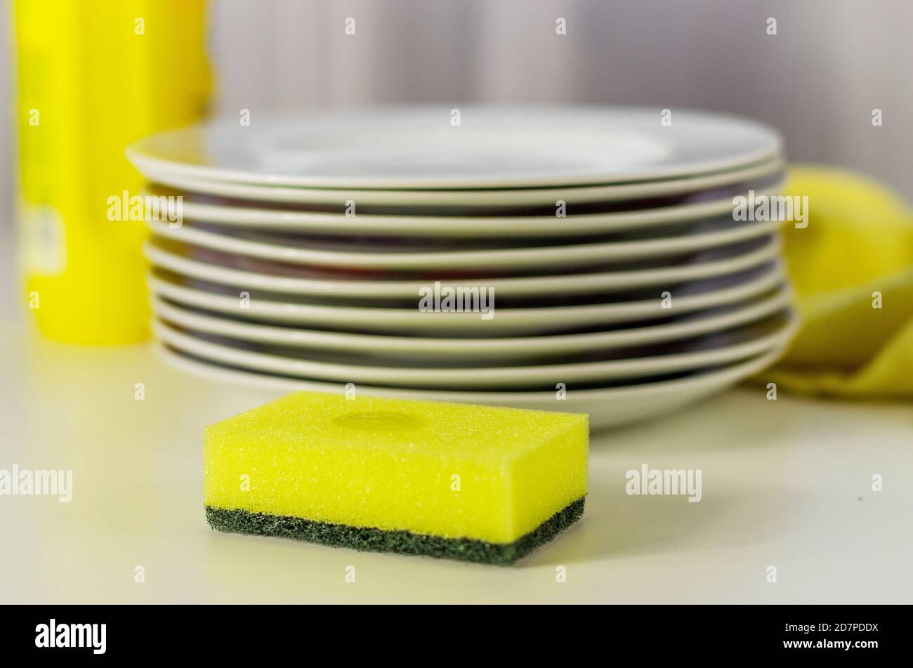 Bottle of dishwashing liquid and stack of utensils isolated on white