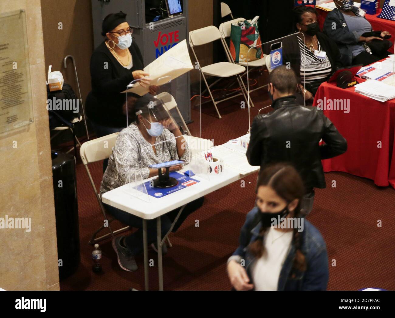 Workers help voters prepare to cast their ballot at a polling site on the the first day of early voting for the 2020 election in New York City on Saturday, October 24, 2020. New York City voters for the first time have the option for early voting for the 2020 election and some waited online hours before their polling site opened at 10 a.m. Photo by John Angelillo/UPI Credit: UPI/Alamy Live News Stock Photo