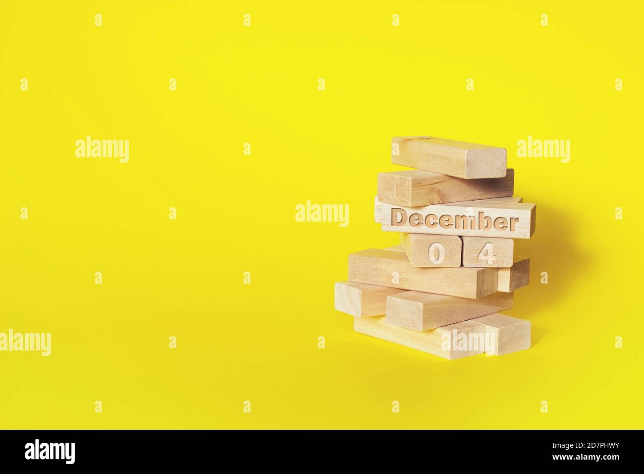 December 4th. Day 4 of month, Calendar date. Wooden blocks folded into the tower with month and day on yellow background, with copy space. Winter mont Stock Photo