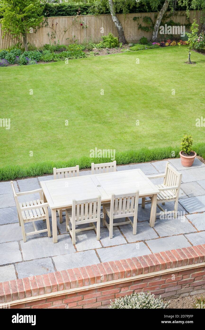 Large back garden in UK in summer, with wooden furniture on a garden patio terrace Stock Photo