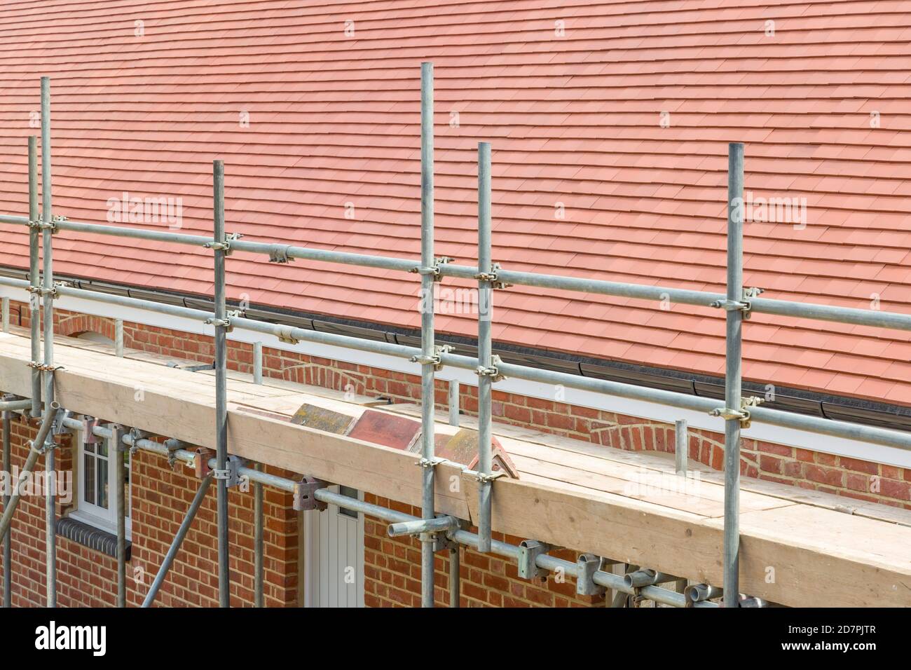 Scaffolding outside a UK house with a plain clay tile pitched roof Stock Photo