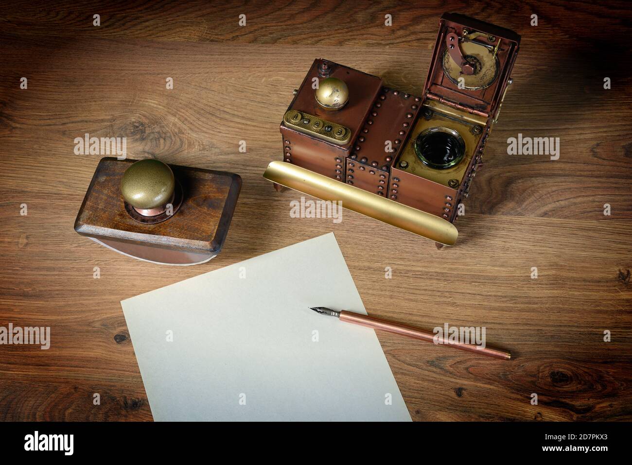 Top view of sheet of paper at wooden vintage desk. ink pen, inkstand with black ink and paperweight. Stock Photo