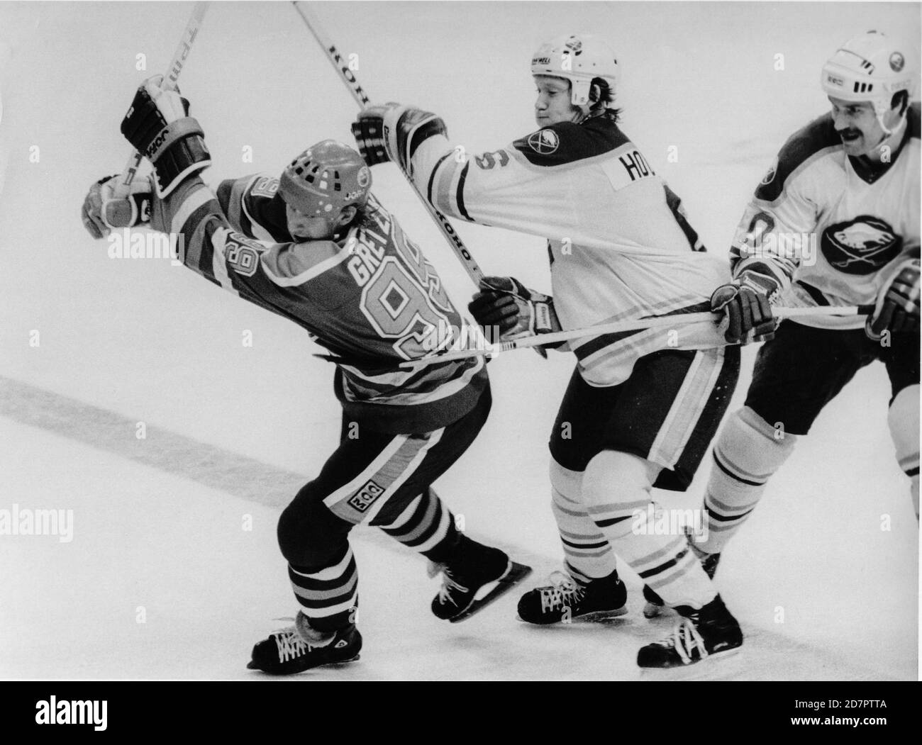 Edmonton Oilers Wayne Gretzky, left, (99)  is checked by Buffalo Sabres Phil Housley, center, and Brent Peterson in Buffalo, New York on January 13, 1985. Photo by Francis Specker Stock Photo