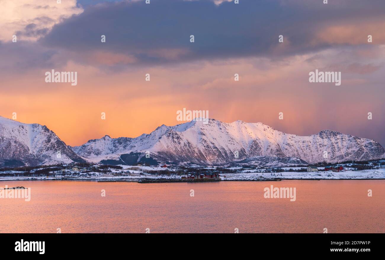 Snowy landscape at sea and fjord, cloud atmosphere, warm evening light, Nordland, Lofoten, Norway Stock Photo