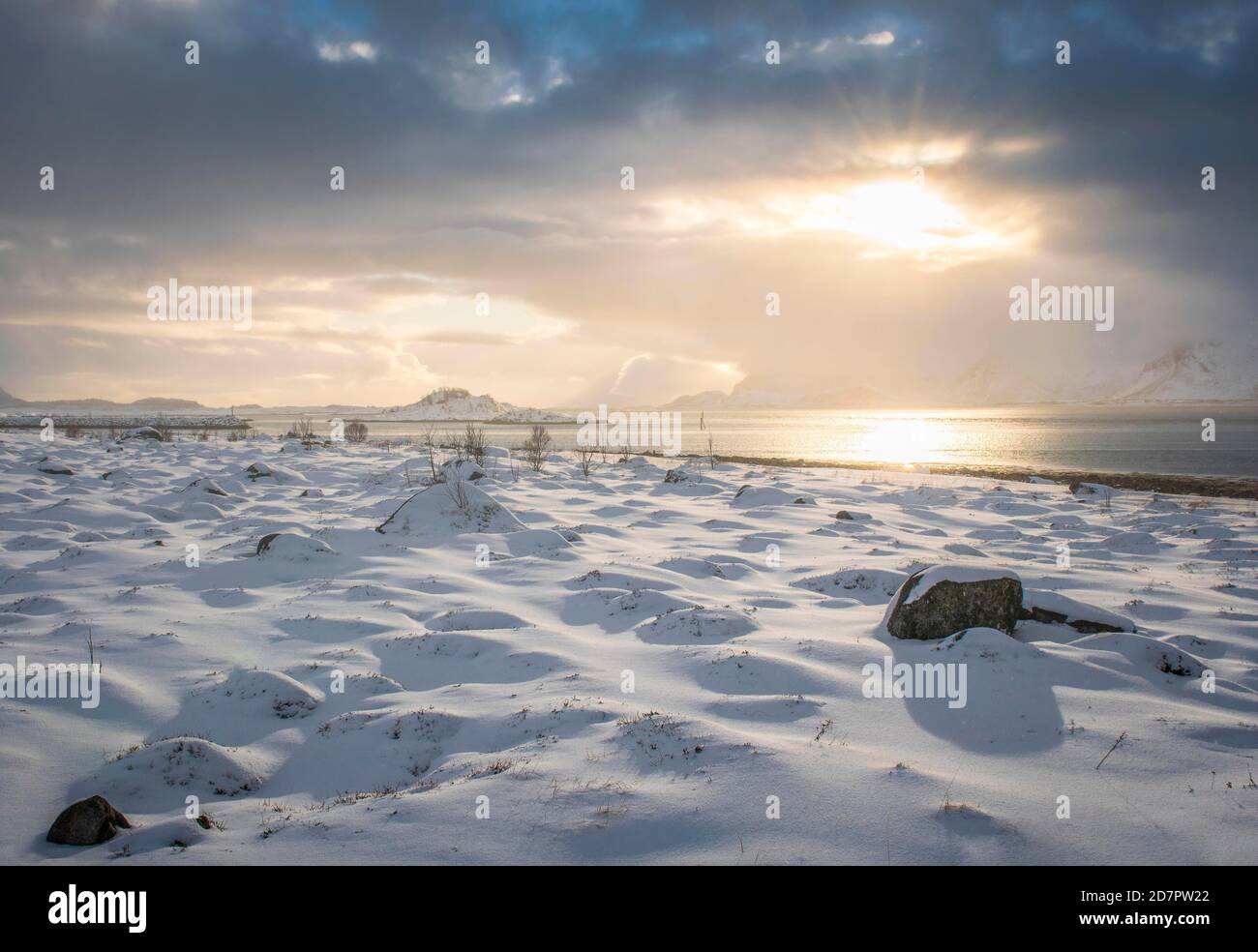Snowy landscape at sea and fjord, cloud atmosphere, warm sunlight, Nordland, Lofoten, Norway Stock Photo