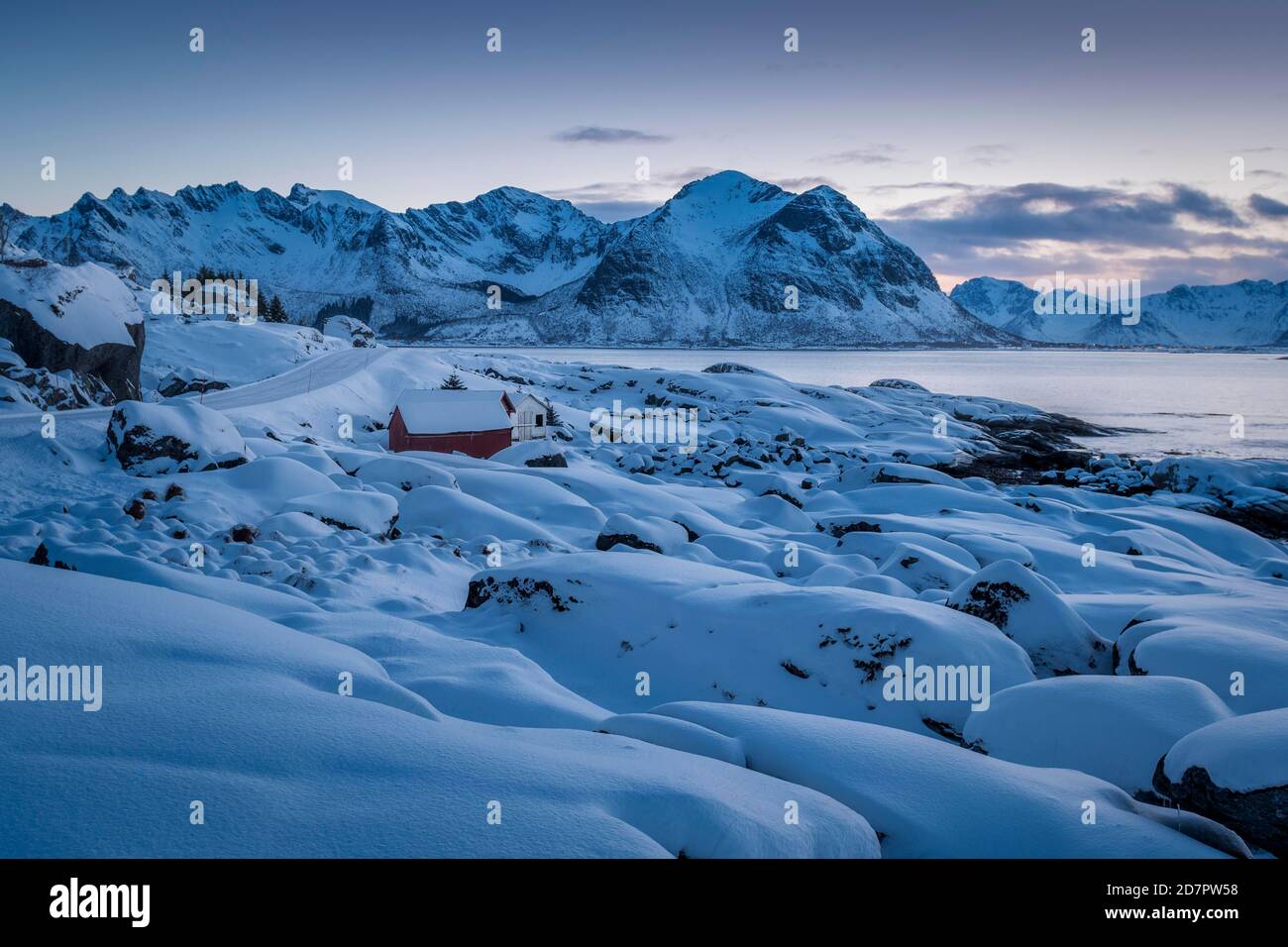 Snowy winter landscape by the sea, wooden cabin on the coast, mountains in the back, Nordland, Lofoten, Norway Stock Photo