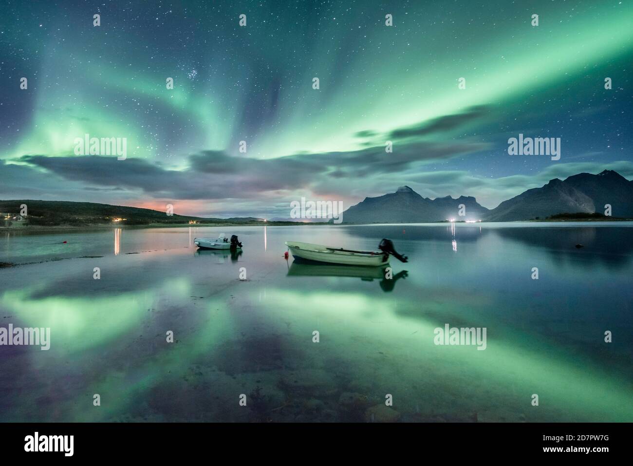 Small (Aurora borealis) motorboats anchoring in a bay, night view