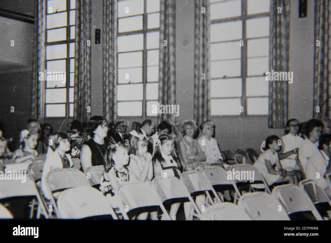 Fine 1970s vintage black and white photography of an audience listening and watching quietly while sitting in an auditorium. Stock Photo
