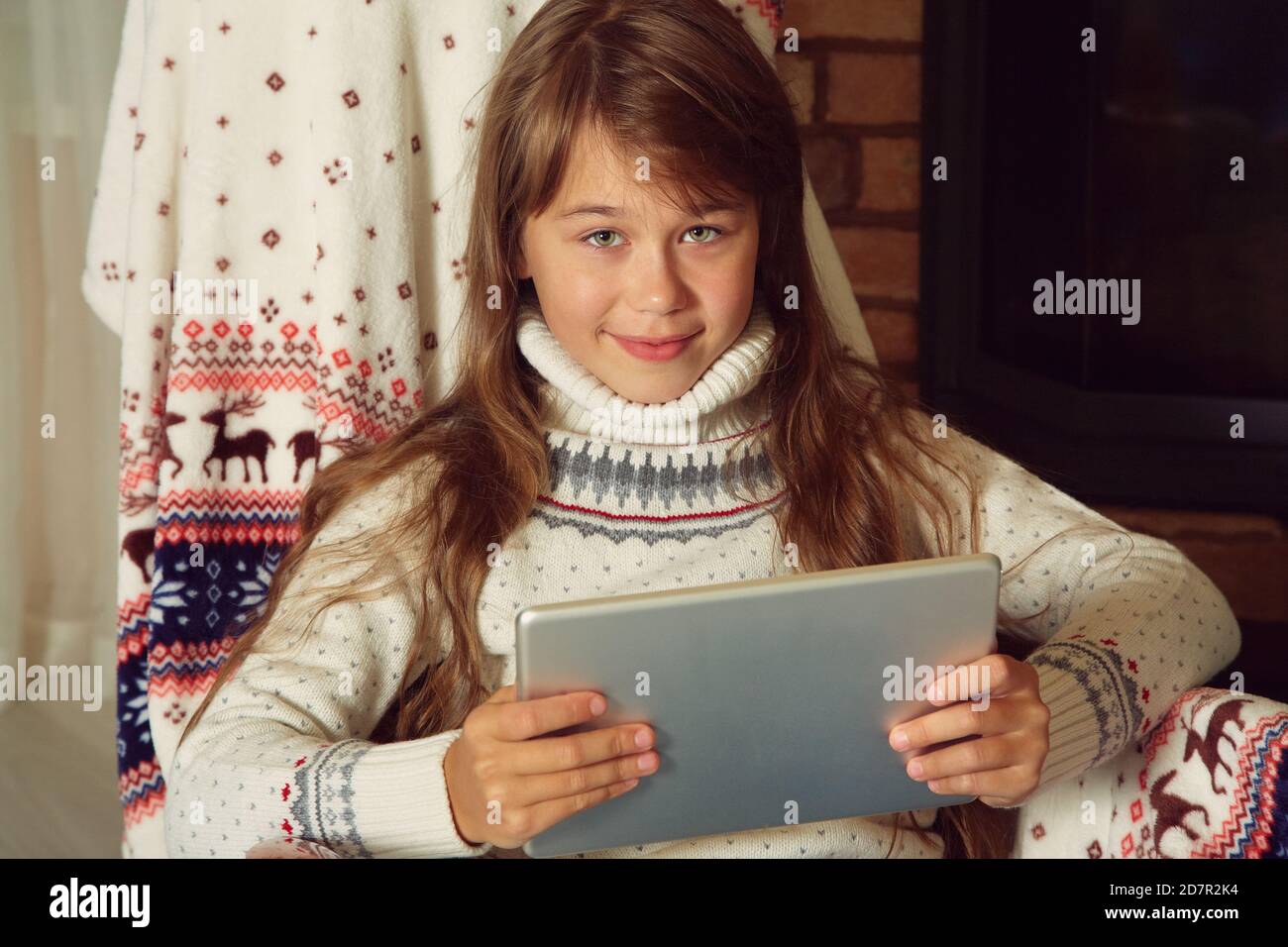 Cute teenage girl with tablet computer near Christmas tree Stock Photo