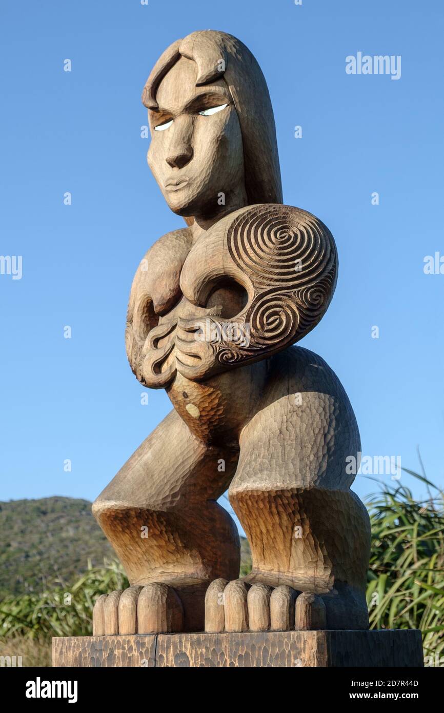 Hinerangi, a hand carved Maori statue stands on the coastline looking out to sea for her drowned lover. West coast of New Zealand Stock Photo